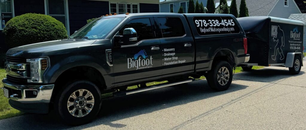 Bigfoot Construction team standing in front of branded van, smiling and ready for service